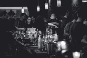 Photo prise derrière le comptoir d'un bar plein (noir & blanc)