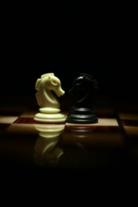 Deux cavaliers (un blanc et un noir) se font face sur un plateau d'échecs